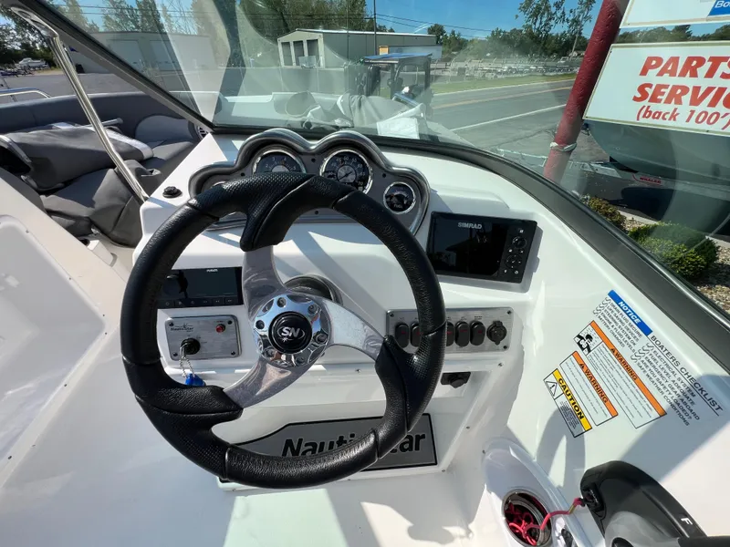 Slide: The Image of 2023 NauticStar 203 DC boat dashboard with steering wheel and control panel. - 13