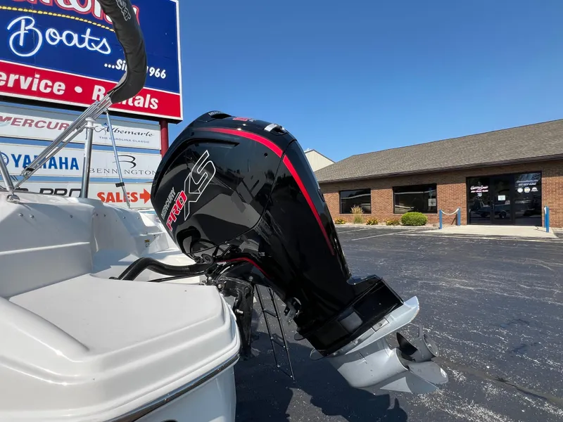 Slide: The Image of 2023 NauticStar 203 DC boat with powerful outboard motor in dealership lot. - 6