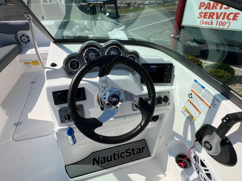 Slide: The Image of 2023 NauticStar 203 DC boat dashboard with steering wheel and control panel. - 9