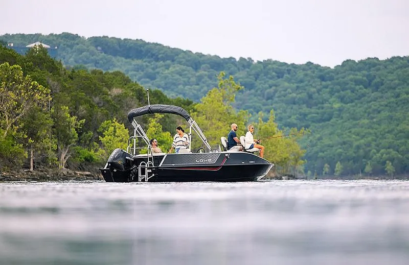 Slide: The Image of 2025 Lowe Deck SD224 boat cruising on a scenic lake with lush green hills. - 31