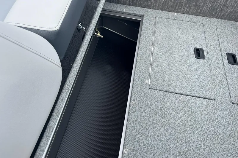 Slide: The Image of 2025 Lowe Deck SD224 boat storage compartment with gray seating and textured flooring. - 33