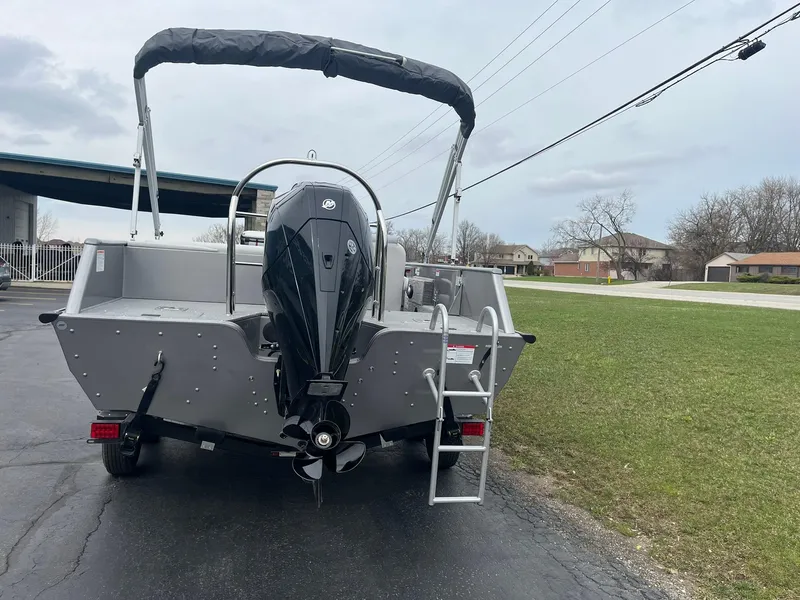 Slide: The Image of 2025 Lowe Deck SD224 boat with outboard motor and ladder, parked on pavement. - 6