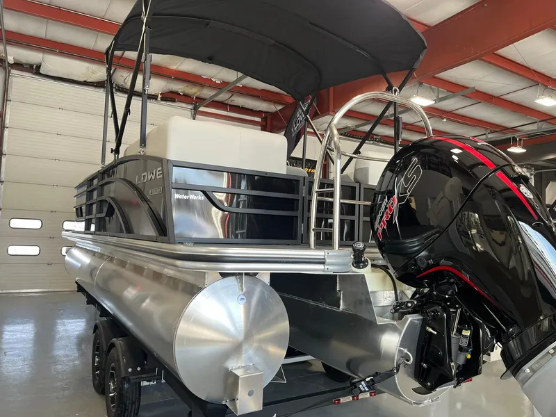 Slide: The Image of 2025 Lowe SS 230 WV pontoon boat with canopy and powerful outboard motor in a showroom. - 27