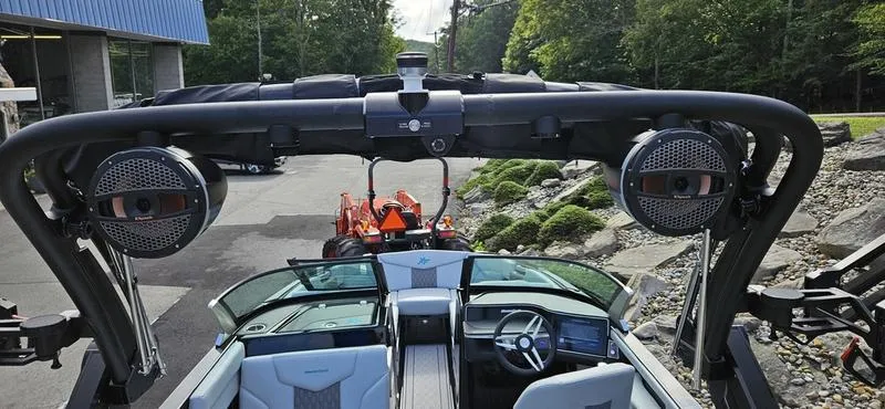 Slide: The Image of 2025 MasterCraft XT24 boat interior with speakers and steering wheel, parked outdoors. - 10