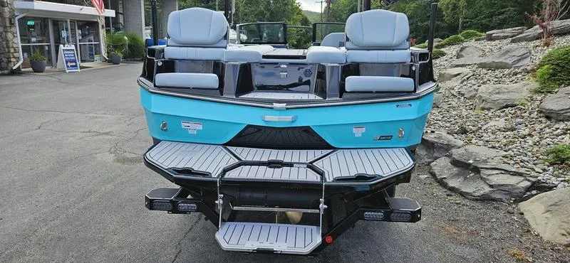 Slide: The Image of 2025 MasterCraft XT24 boat, rear view, blue exterior, docked on pavement. - 3