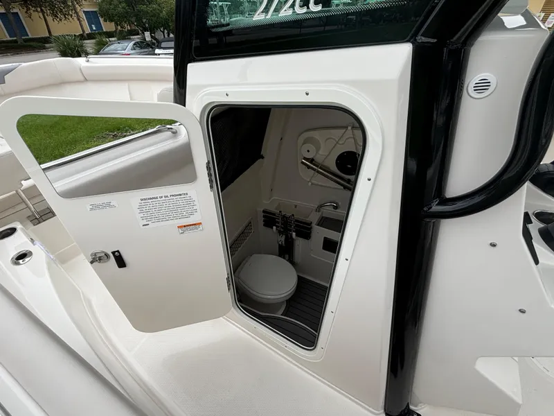 Slide: The Image of 2025 Sailfish 272 CC boat interior with open door revealing compact restroom. - 20