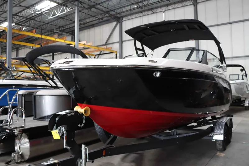 Slide: The Image of 2025 Yamaha Boats 222SD in showroom, black and red hull, on trailer. - 6