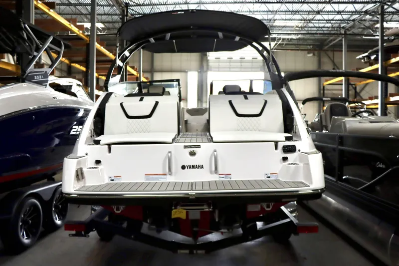 Slide: The Image of 2025 Yamaha Boats 222SD in showroom, rear view with seating and storage. - 9