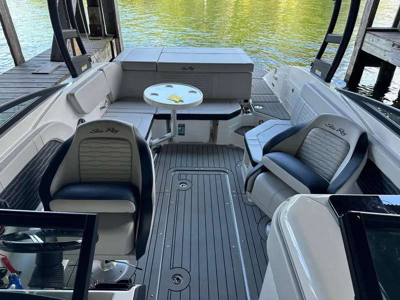 Slide: The Image of 2022 Sea Ray 230SPX boat interior with seating and table, docked by the water. - 7
