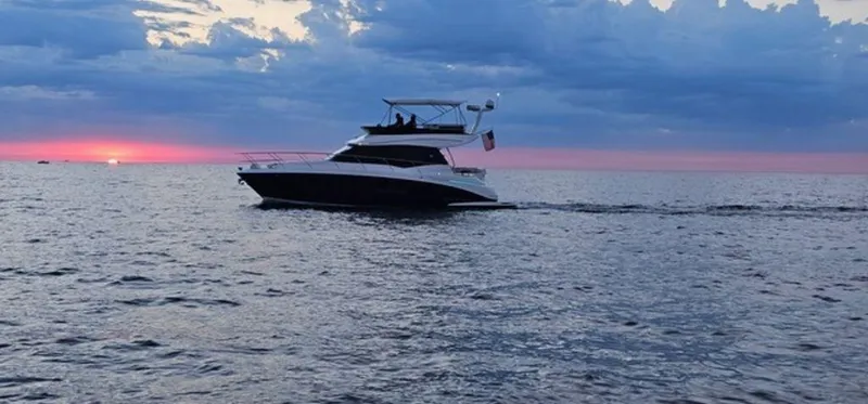 Slide: The Image of 2024 Regal 42 Fly yacht cruising at sunset on open water. - 2