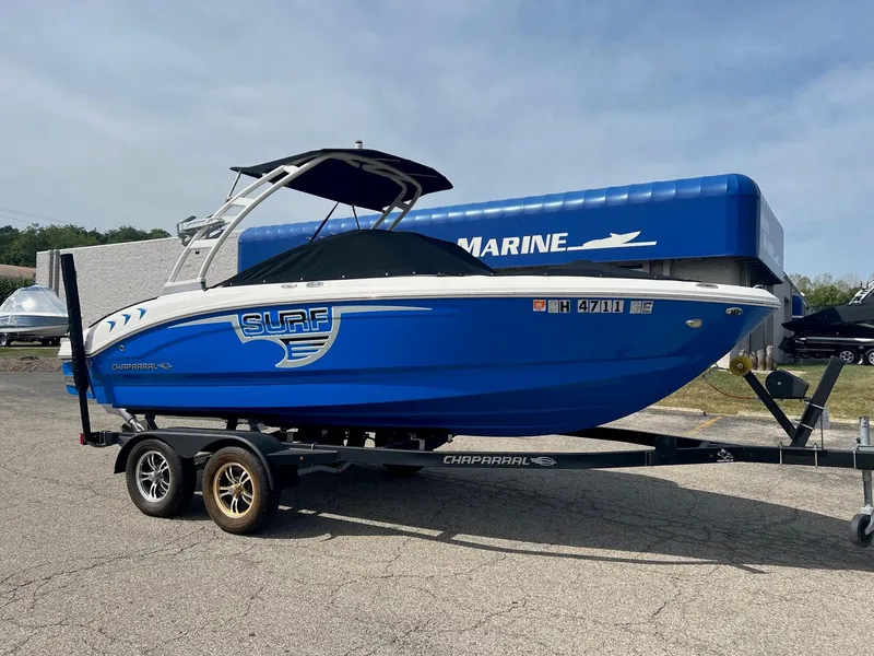 Slide: The Image of 2021 Chaparral 21 Surf boat on trailer, blue and white design, parked outdoors. - 9