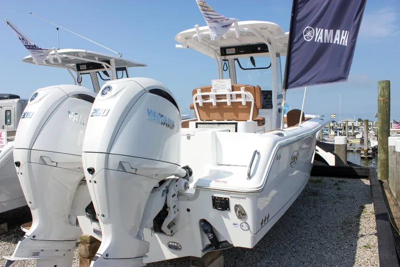 Slide: The Image of 2025 Sea Hunt Gamefish 25 boat with dual Yamaha engines at a marina. - 10