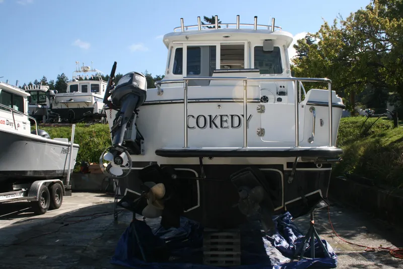 Slide: The Image of 2005 Ocean Sport Roamer 30' boat on land, rear view, with trees and sky background. - 15
