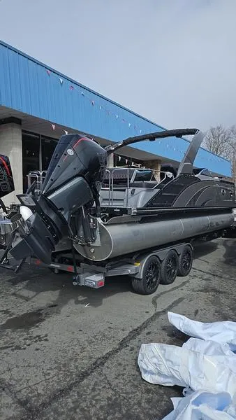 Slide: The Image of 2024 Bennington QX 27 QXSBWA X2 Swingback pontoon boat on trailer, outdoor setting. - 5