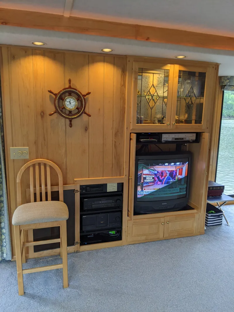 Slide: The Image of 1999 Sumerset 16x78 houseboat interior with wooden paneling, TV, and nautical decor. - 13