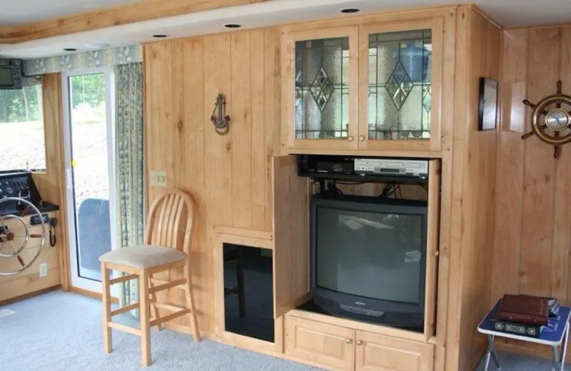 Slide: The Image of 1999 Sumerset 16x78 houseboat interior with wood paneling, TV, and nautical decor. - 15