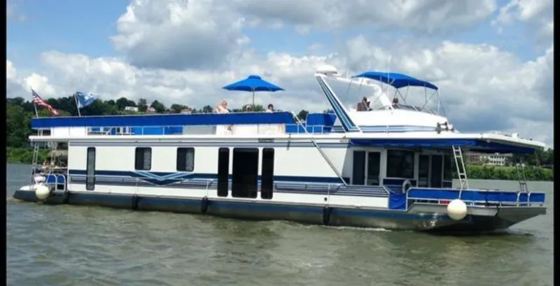 Slide: The Image of 1999 Sumerset 16x78 houseboat on a lake with blue accents and sun umbrellas. - 2
