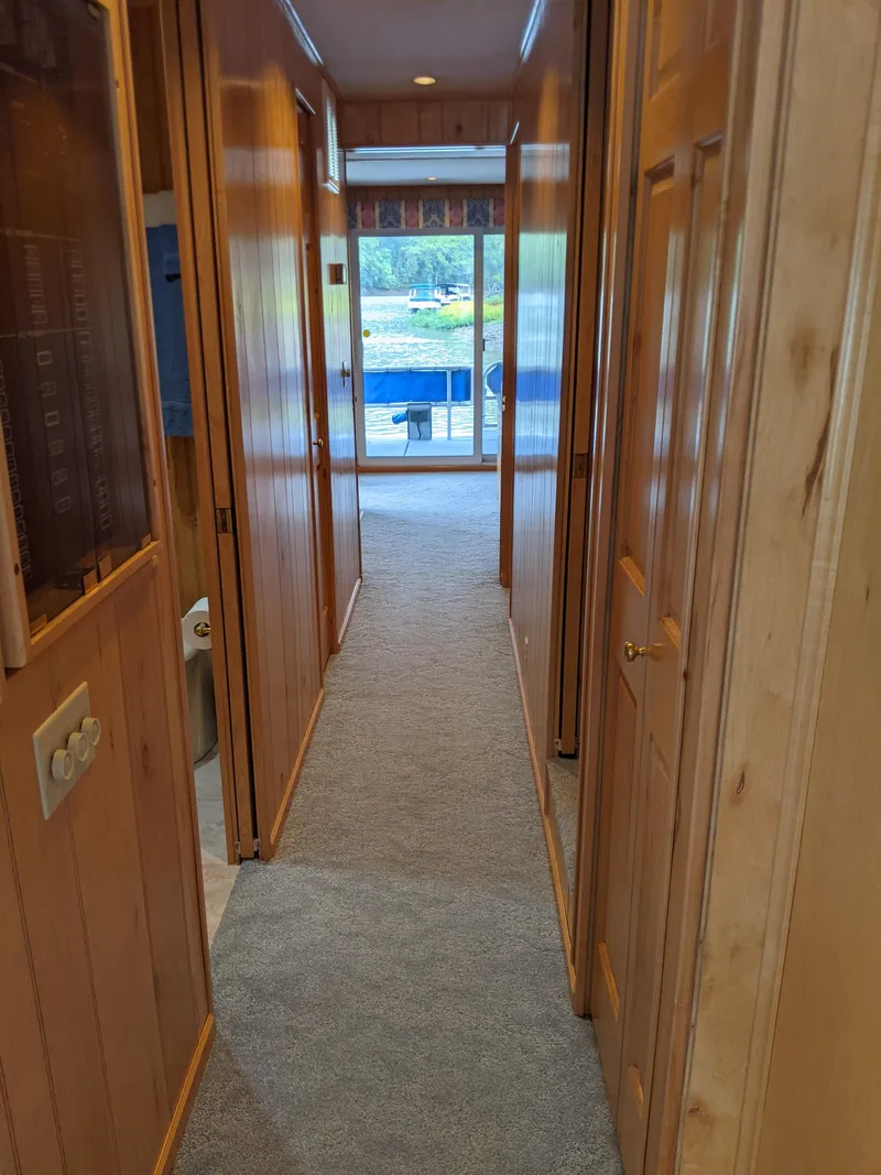 Slide: The Image of Narrow hallway in a 1999 Sumerset 16x78 houseboat with wood paneling and carpet. - 22
