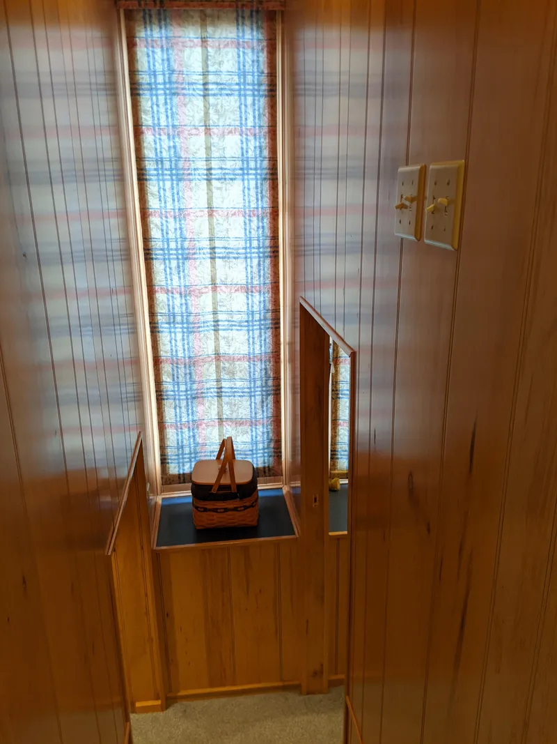 Slide: The Image of Wood-paneled interior of a 1999 Sumerset 16x78 houseboat with a window and plaid curtain. - 26