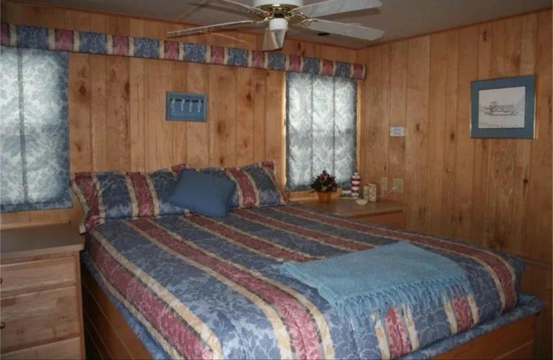 Slide: The Image of Cozy bedroom in 1999 Sumerset 16x78 houseboat with wood paneling and striped bedding. - 32