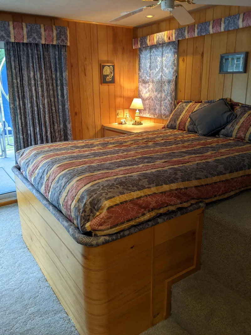 Slide: The Image of Cozy bedroom in 1999 Sumerset 16x78 houseboat with wood paneling and colorful bedding. - 33