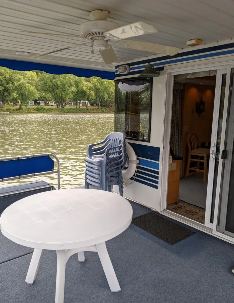 Slide: The Image of 1999 Sumerset 16x78 houseboat deck with table, chairs, and river view. - 4