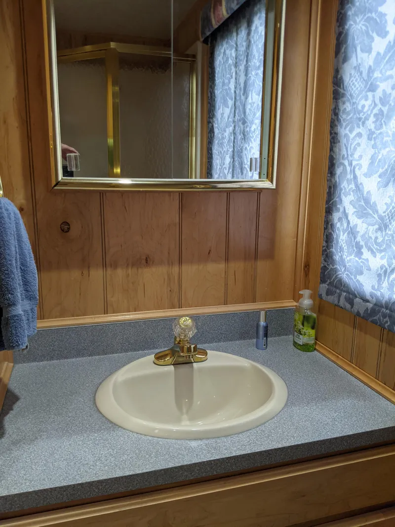 Slide: The Image of Bathroom sink with wooden paneling and floral curtains in a 1999 Sumerset 16x78 houseboat. - 40