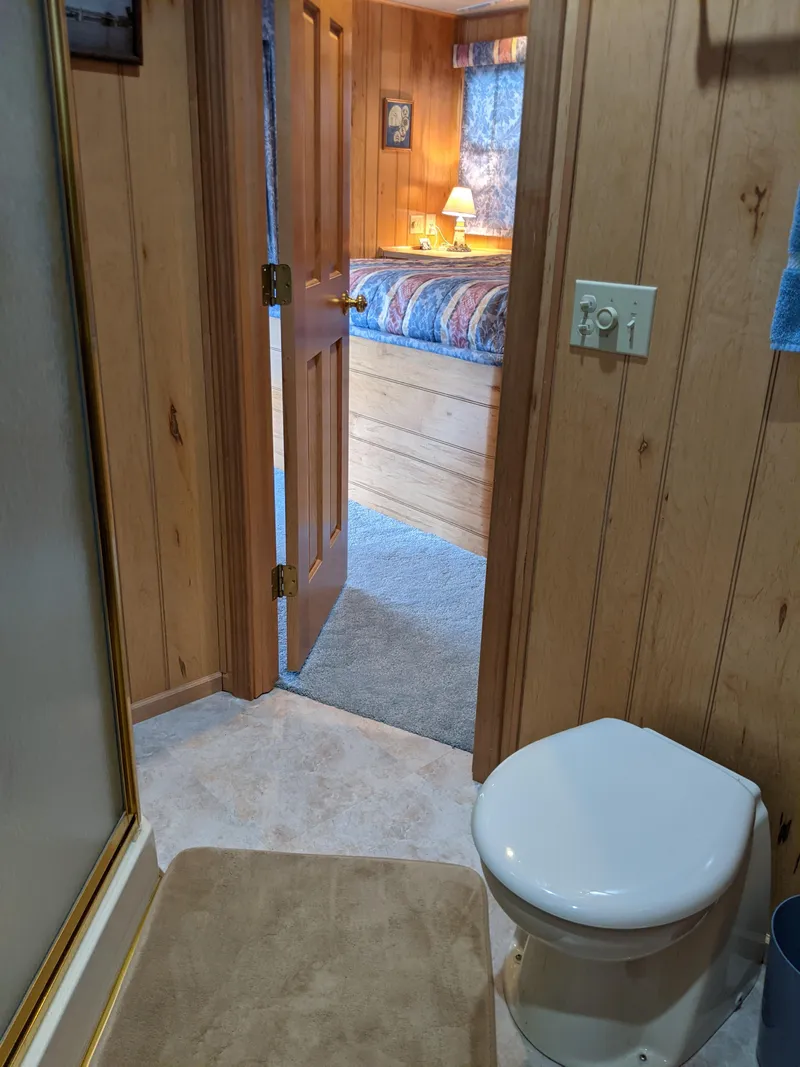 Slide: The Image of 1999 Sumerset 16x78 houseboat bathroom with wood paneling and view into cozy bedroom. - 41