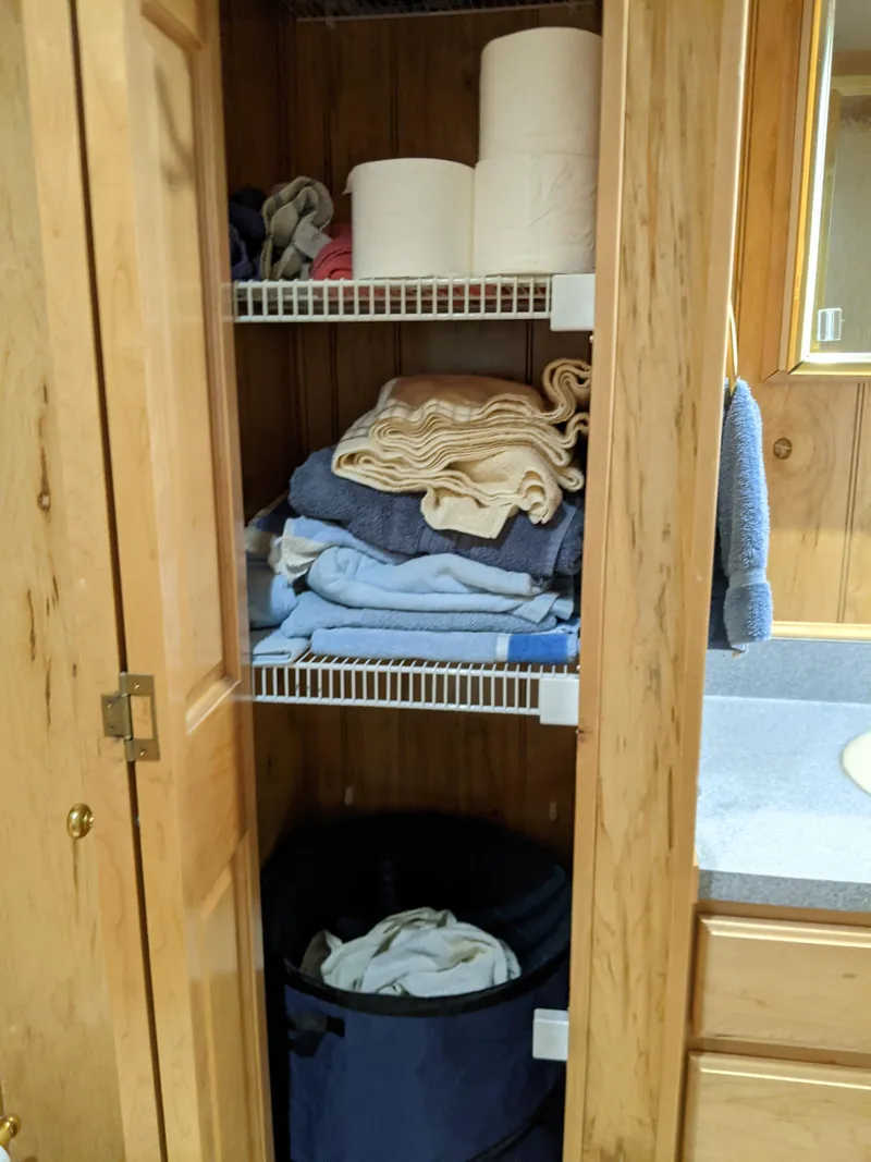 Slide: The Image of Wooden cabinet with towels, toilet paper, and laundry basket in a 1999 Sumerset 16x78 houseboat. - 42
