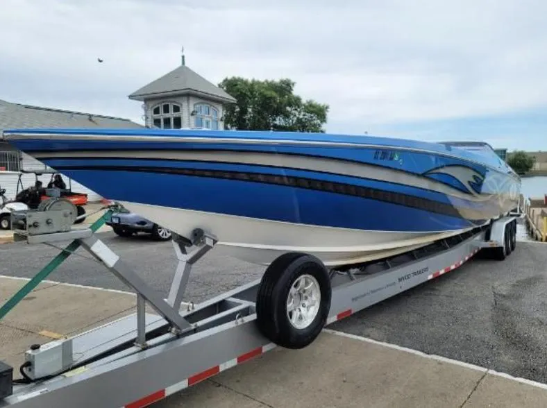Slide: The Image of 2009 Cigarette 46' Rider XP boat on trailer, blue and white design, parked near waterfront. - 2