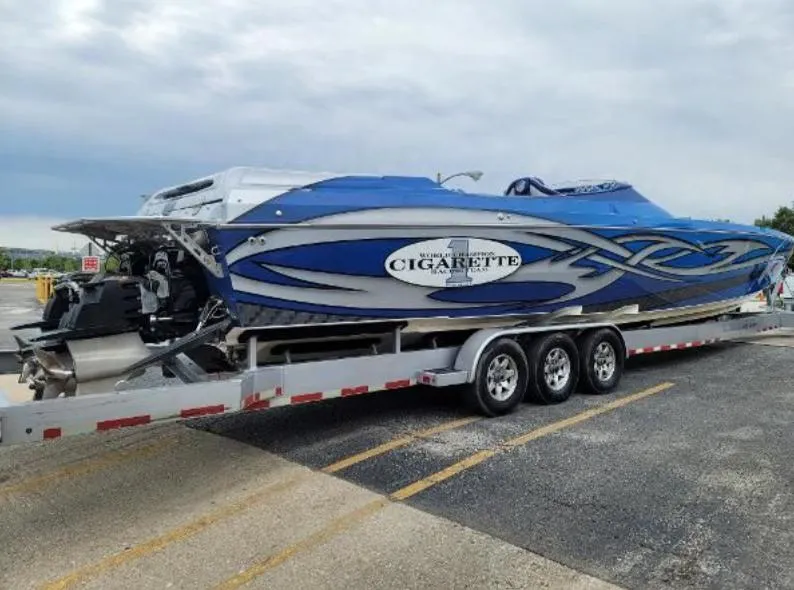 Slide: The Image of 2009 Cigarette 46' Rider XP boat on trailer, blue and white design, parked outdoors. - 5