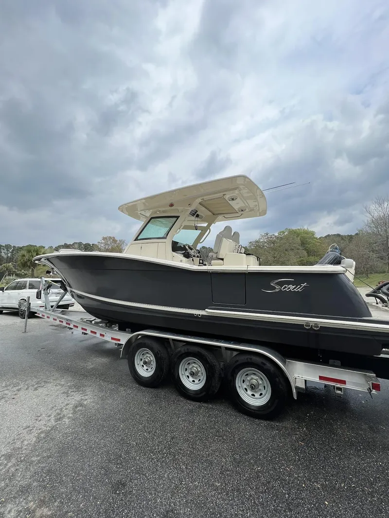 The Image of 2021 Scout 305 LXF boat on trailer under cloudy sky. - 0