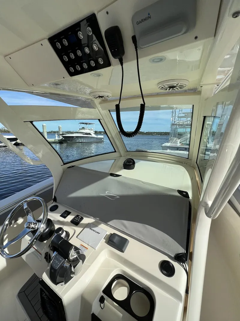 Slide: The Image of 2021 Scout 305 LXF boat interior with steering wheel and control panel, docked by the water. - 4