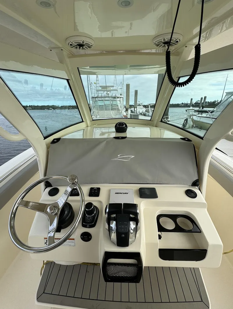 Slide: The Image of 2021 Scout 305 LXF boat helm with steering wheel and controls, docked at marina. - 5