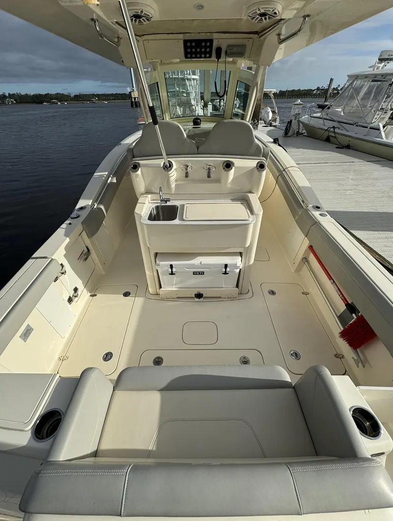 Slide: The Image of 2021 Scout 305 LXF boat interior with seating and helm, docked by the water. - 6
