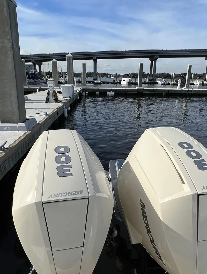 Slide: The Image of 2021 Scout 305 LXF boat with twin Mercury engines docked at marina. - 7
