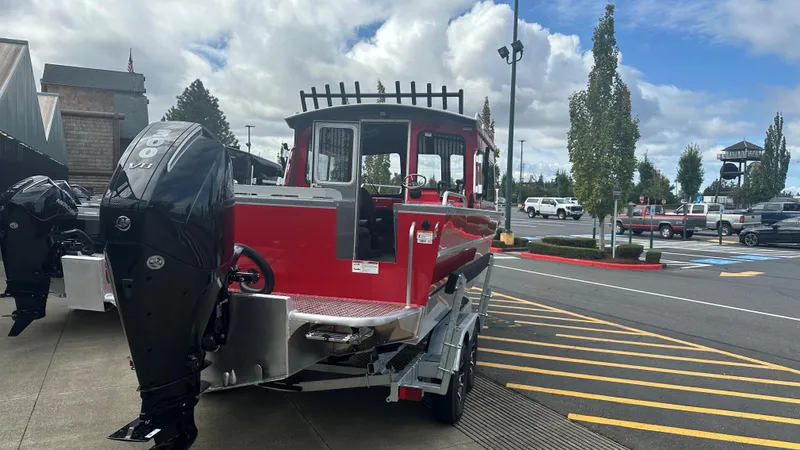 Slide: The Image of 2024 Spartan 220 Maximus Pro boat with outboard motor and trailer in a parking lot. - 2