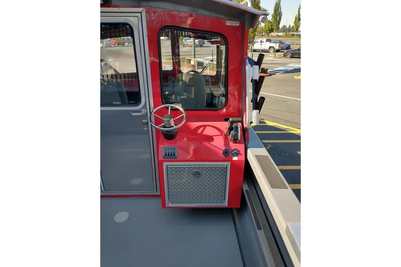 Slide: The Image of Red 2024 Spartan 220 Maximus Pro boat helm with steering wheel and control panel. - 9