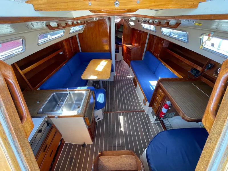 Slide: The Image of Interior of 1980 Catalina 38 sailboat with blue seating, wooden finishes, and compact kitchen. - 15