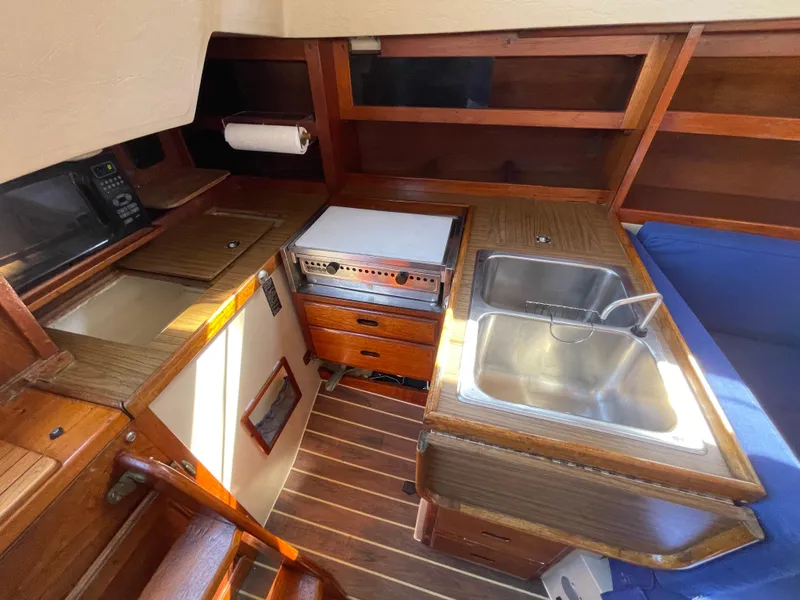 Slide: The Image of 1980 Catalina 38 yacht interior kitchen with sink, stove, and wooden cabinetry. - 16