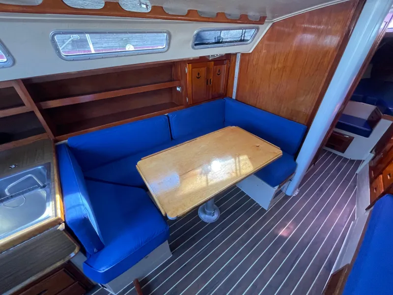Slide: The Image of Interior of 1980 Catalina 38 sailboat with blue seating and wooden table. - 18