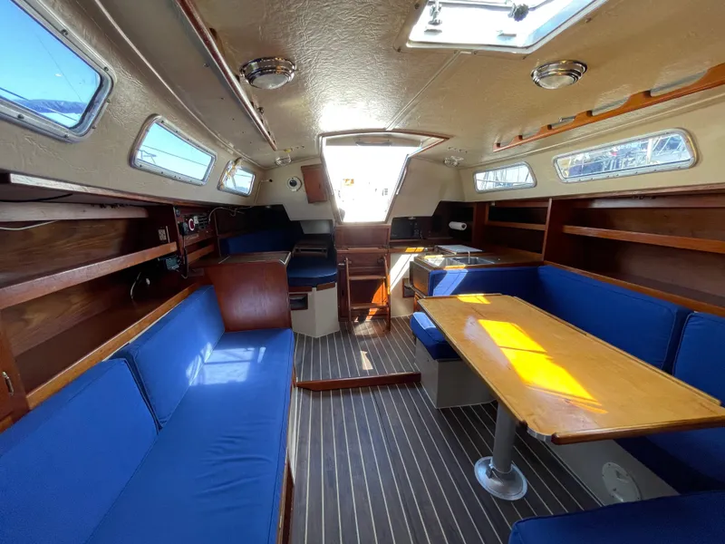 Slide: The Image of Interior of 1980 Catalina 38 sailboat with blue seating and wooden table. - 24