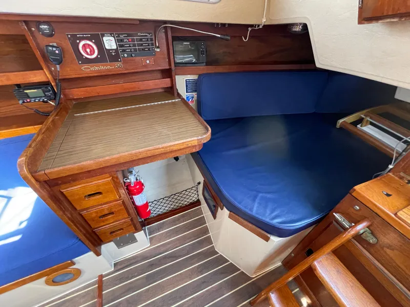 Slide: The Image of 1980 Catalina 38 sailboat interior with wooden cabinetry, blue cushions, and navigation equipment. - 25
