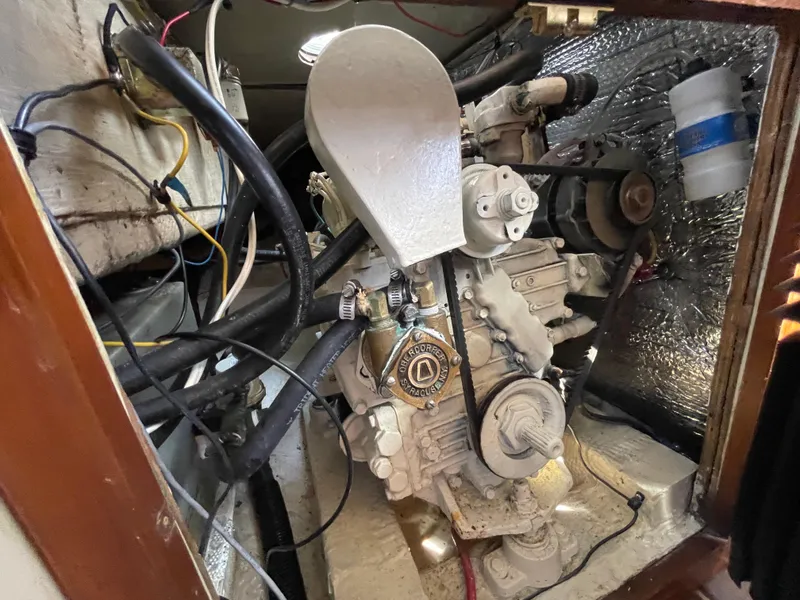 Slide: The Image of Engine compartment of a 1980 Catalina 38 sailboat, featuring a diesel engine and various hoses. - 32