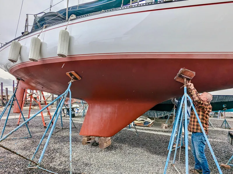 Slide: The Image of Man inspecting 1980 Catalina 38 sailboat hull on stands in a boatyard. - 33