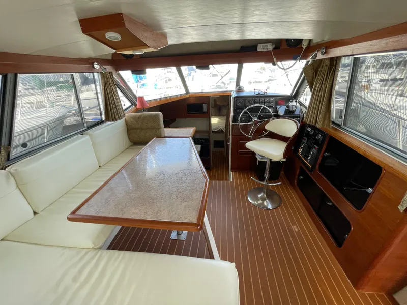 Slide: The Image of 1989 Bayliner 3288 interior with helm, seating, and table, showcasing classic nautical design. - 13
