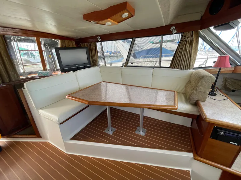 Slide: The Image of Interior of 1989 Bayliner 3288 with dining area, white seating, and wood accents. - 15