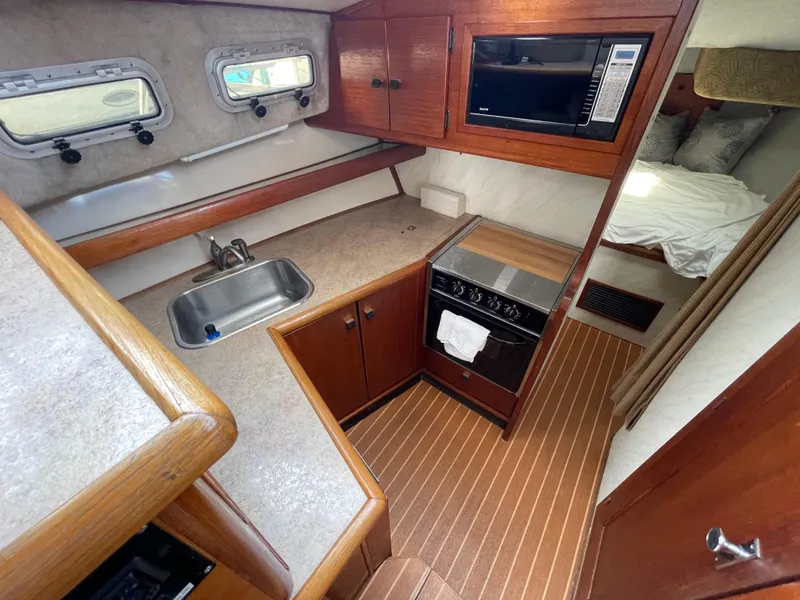 Slide: The Image of 1989 Bayliner 3288 interior with kitchen, sink, stove, microwave, and cozy sleeping area. - 16