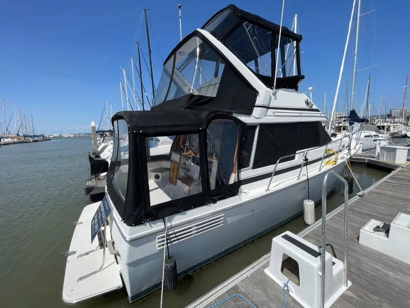 Slide: The Image of 1989 Bayliner 3288 yacht docked at marina, featuring black canopy and sleek design. - 2