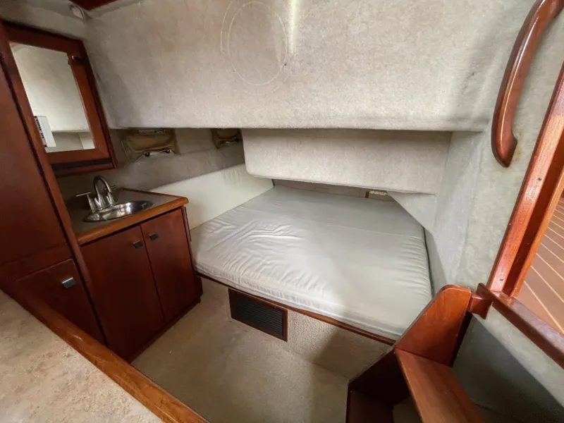 Slide: The Image of 1989 Bayliner 3288 cabin interior with bed, sink, and wooden cabinetry. - 23